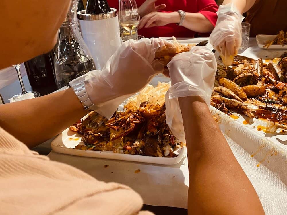 Mit Händen in Einweghanschuhen Garnele schälen am Seafood Table.