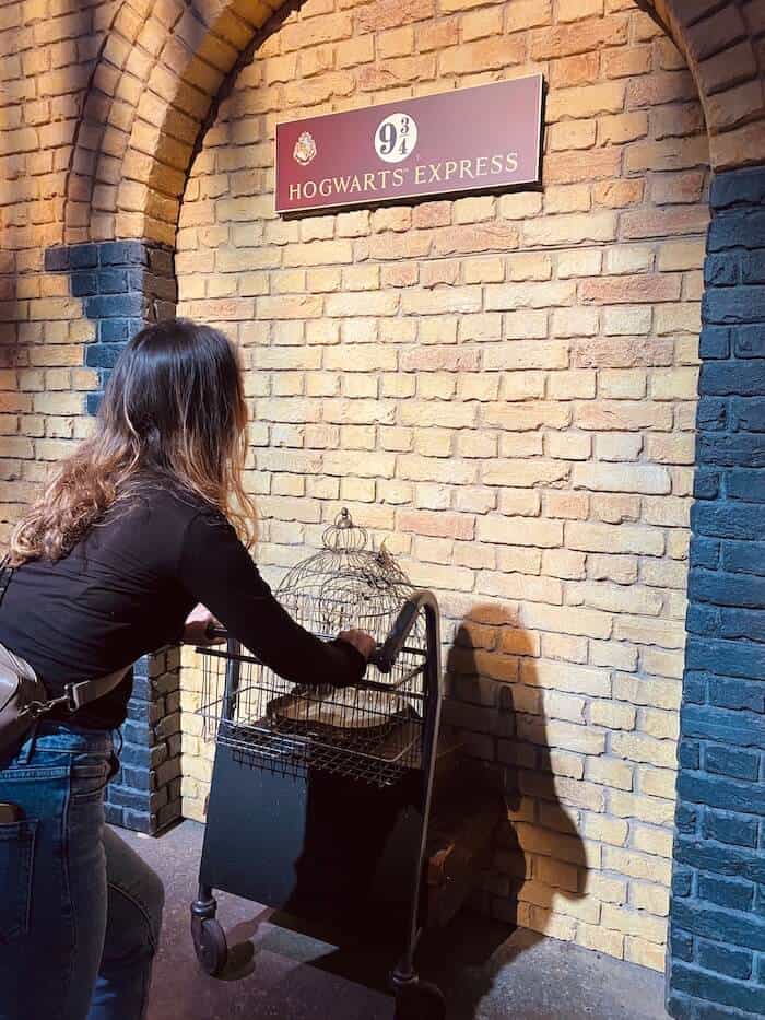 Der bekannte Gleis 9 3/4 aus der Harry Potter Ausstellung. Halber Kofferwagen, der zur Hälfte in der Wand drinnen ist und Mädchen, welcher den schiebt.