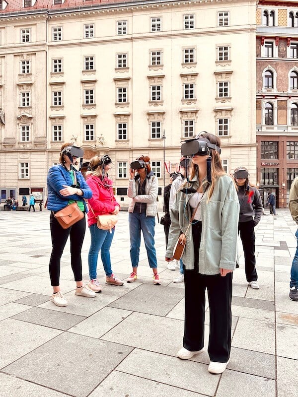 Eine Gruppe Menschen stehen am Platz vor dem Stephansdom und neben an der VR Tours Vienna teil. Sie tragen alle die Brille.