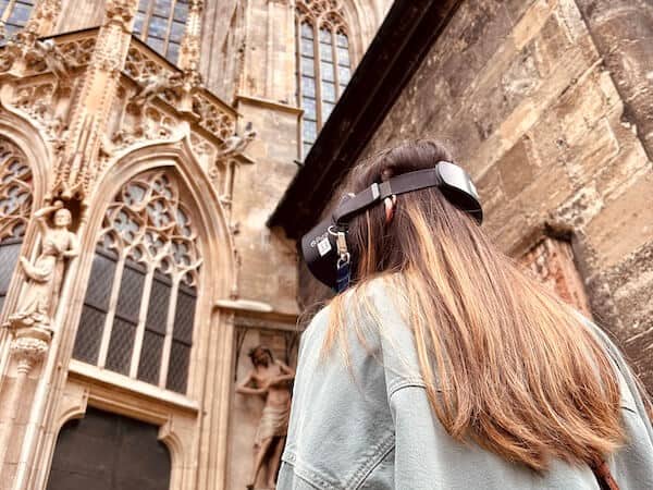 Mädchen von hinten steht vor dem Stephansdom und hat eine VR Brille aufgesetzt.