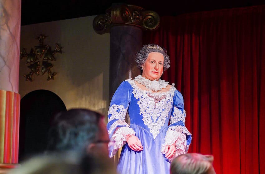 Habsburger Show bei Time Travel Wien. Maria Theresia Wachsfigur vor einem roten Bühnenvorhang
