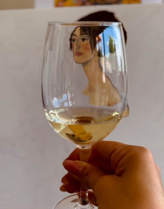 Weinglas und im Hintergrund ein Selbstgemaltes Portrait von Lady mit Fan von Klimt