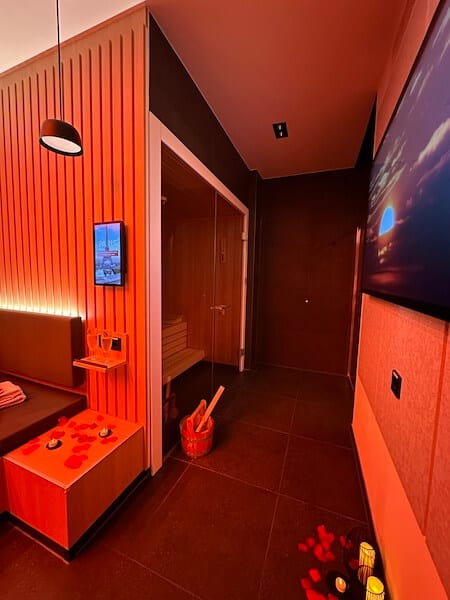 Sauna, Bildschirm und Liegebereich des Well-One im roten Licht.