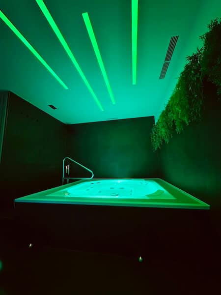 Whirlpool in der Well-One privaten Wellness Kabine im grünen Ambiente-Licht.