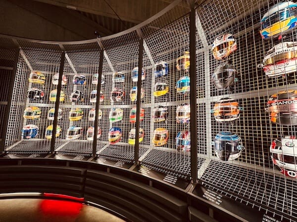 Viele Helme von Formel 1 Fahrer aufgestellt auf der Wand.