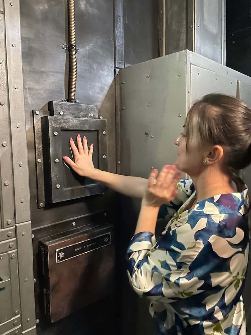 Frau hält Hand an eine Vorrichtung eines neuen Escape Rooms.