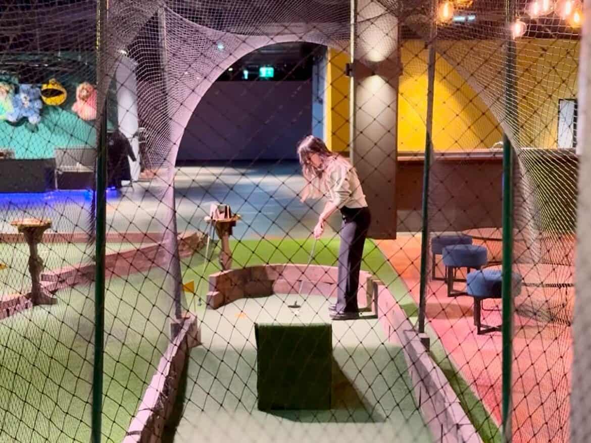 Frau in der Mitte spielt Minigolf