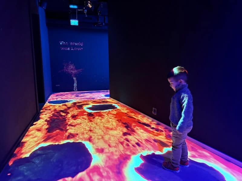 Kind steht auf Stein, projeziert. Der Boden ist Lava.