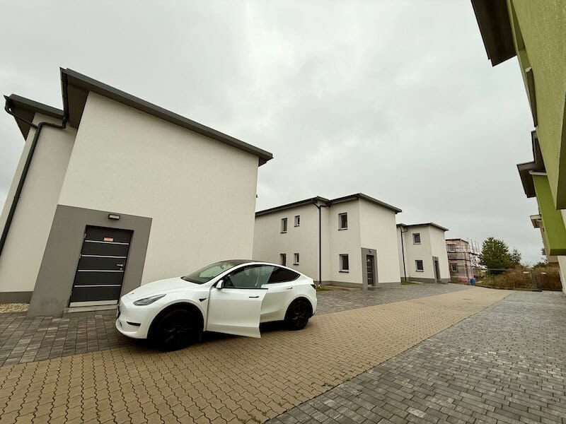 weißes Tesla Auto vor Haus. mit offener Tür - referral code